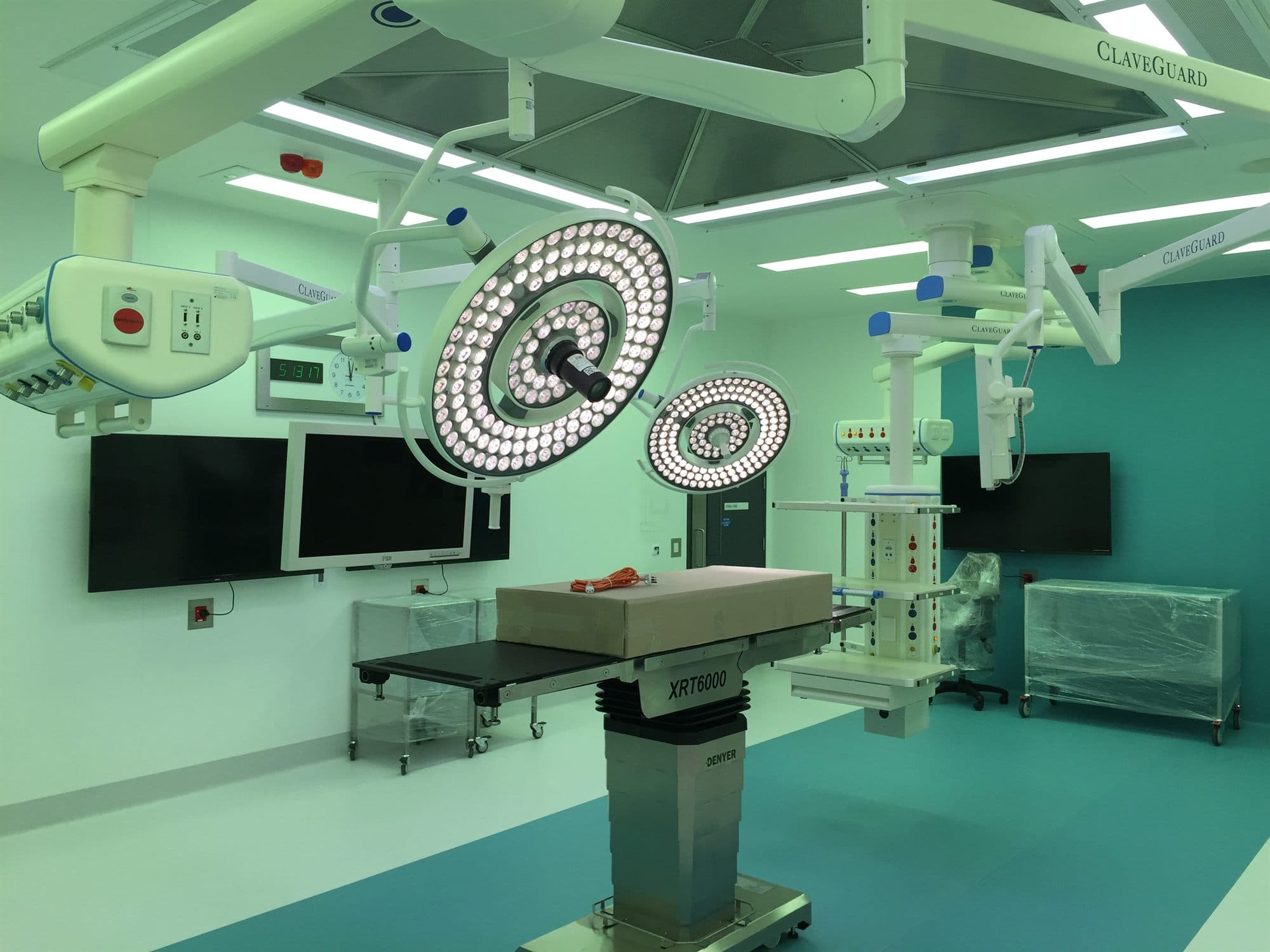 A newly fitted operating theatre with surgical lights, ceiling pendants and an operating table, furniture still in protective wrap.